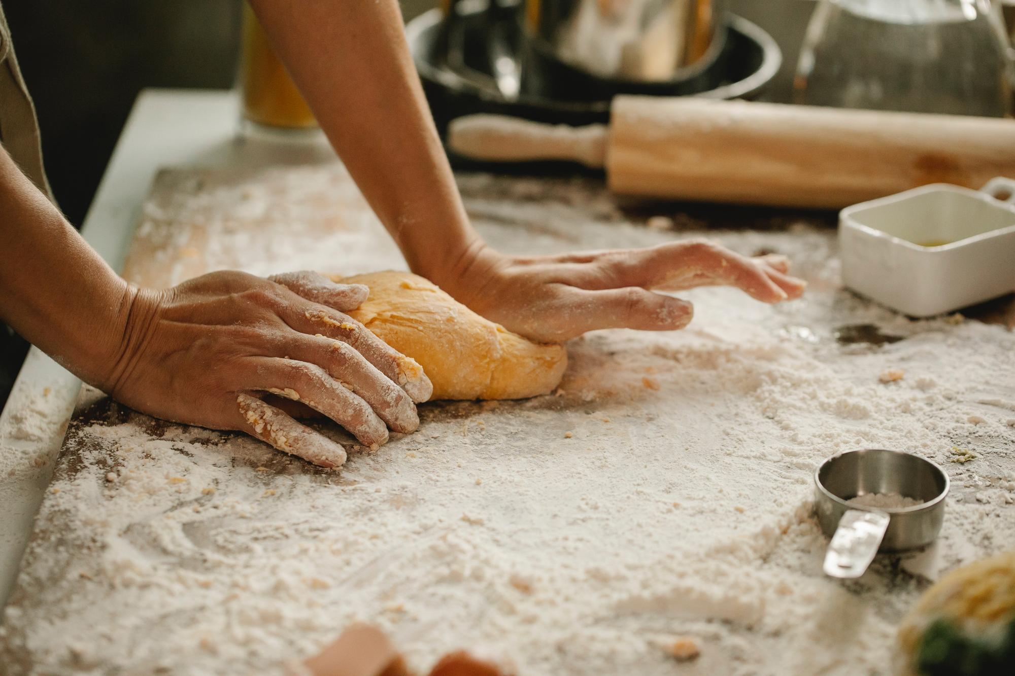 chef hands kneading dough at bench
